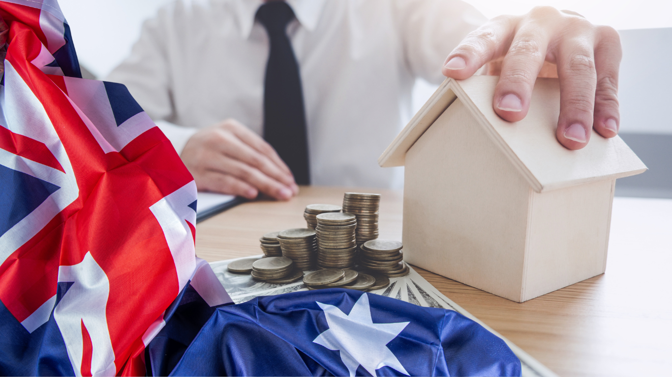 An Australian flag displayed alongside a stack of dollar bills and a small house model, symbolizing financial planning and housing in Australia.